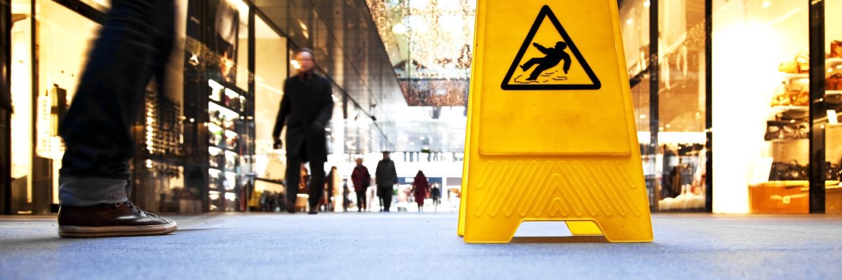 danger sign in a shopping mall, in the background are motion blurred people.